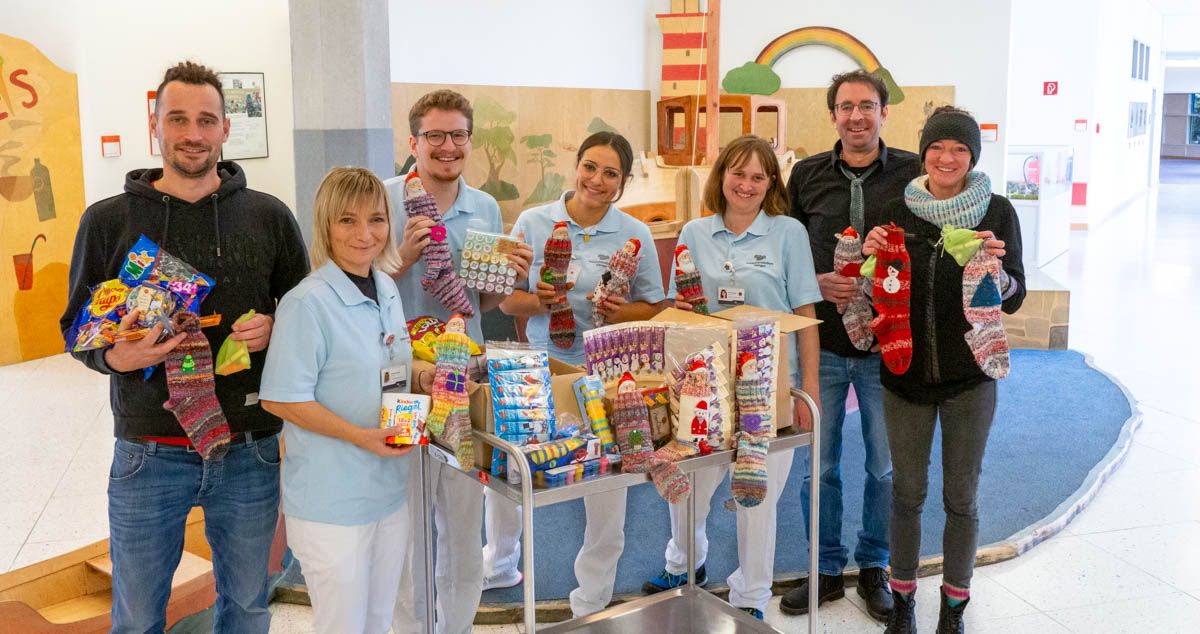 Das Team der Erzieher*innen un d Familie Zwerger mit den Nikolausstrümpfen und Schokolade